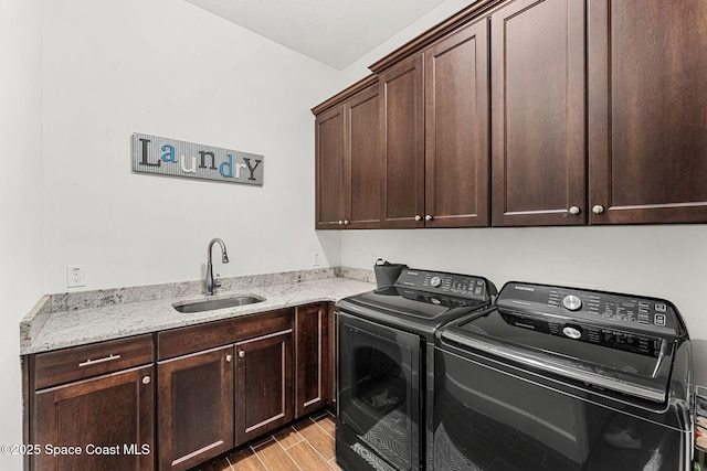 laundry room featuring wood finish floors, washing machine and dryer, cabinet space, and a sink