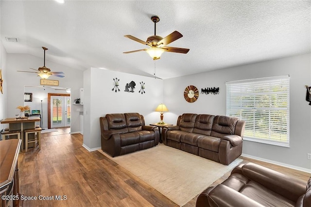 living room with visible vents, wood finished floors, a ceiling fan, and vaulted ceiling