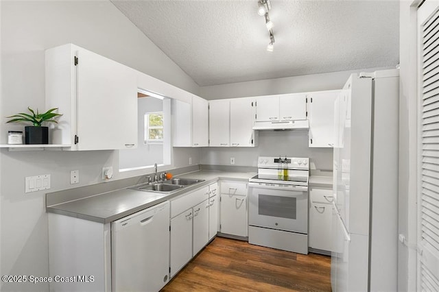 kitchen with a sink, under cabinet range hood, white appliances, a textured ceiling, and dark wood-style flooring