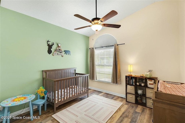 bedroom with lofted ceiling, wood finished floors, baseboards, and ceiling fan