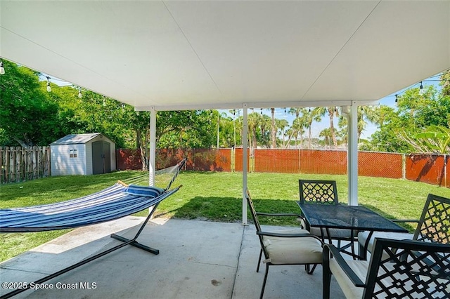 view of patio featuring a fenced backyard, an outdoor structure, outdoor dining space, and a shed