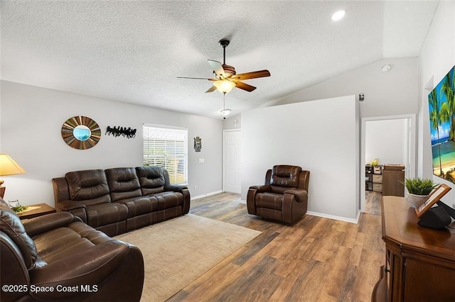 living area featuring wood finished floors, baseboards, ceiling fan, vaulted ceiling, and a textured ceiling