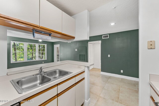 7667 N Wickham Rd Unit 712, Melbourne, FL 32940 - kitchen featuring light countertops, white cabinets, a sink, light tile patterned floors, and baseboards