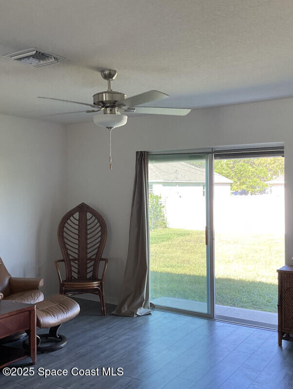 sitting room with visible vents, wood finished floors, a textured ceiling, and ceiling fan