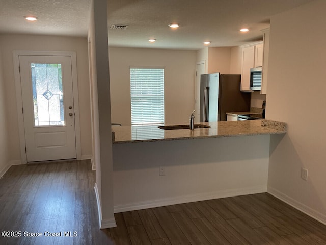 kitchen with dark wood finished floors, a peninsula, white cabinets, and stainless steel appliances