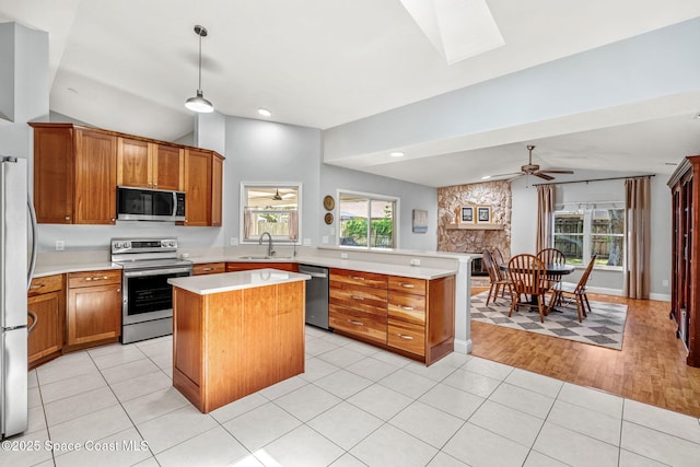 kitchen with stainless steel appliances, light countertops, brown cabinets, lofted ceiling, and a peninsula