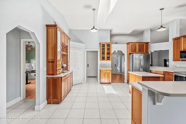 kitchen with appliances with stainless steel finishes, light tile patterned floors, glass insert cabinets, a ceiling fan, and vaulted ceiling
