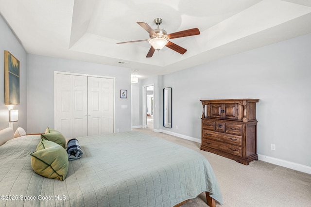 bedroom featuring a raised ceiling, carpet, a closet, and baseboards