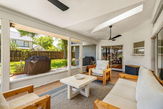 sunroom featuring a ceiling fan, a skylight, vaulted ceiling, and an outdoor living space