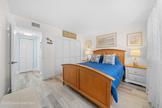 bedroom with a closet, visible vents, baseboards, and light wood-style floors