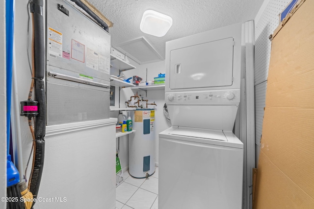 laundry room with laundry area, light tile patterned flooring, water heater, a textured ceiling, and stacked washer / dryer