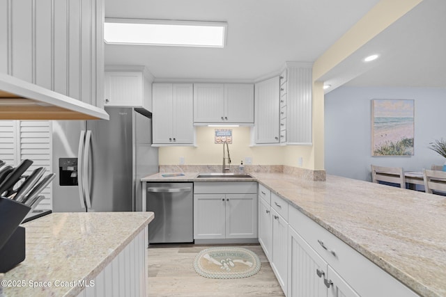 kitchen with white cabinetry, stainless steel appliances, light wood-type flooring, and a sink