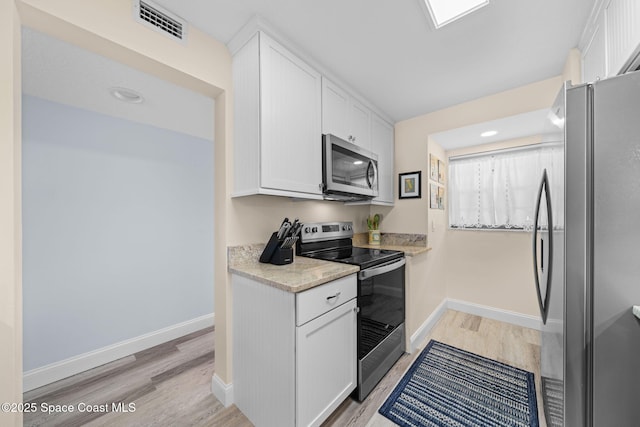 kitchen with white cabinets, baseboards, visible vents, and stainless steel appliances