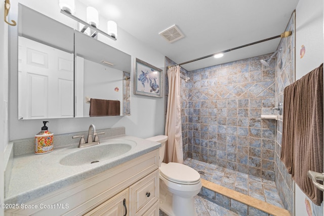 bathroom featuring visible vents, toilet, tiled shower, and vanity