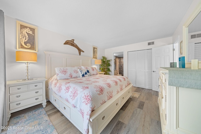 bedroom featuring a closet, ensuite bathroom, visible vents, and light wood finished floors