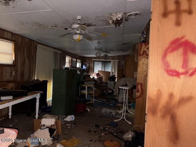 miscellaneous room with a ceiling fan, wood walls, and a wealth of natural light