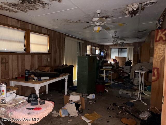 miscellaneous room featuring a ceiling fan and wood walls