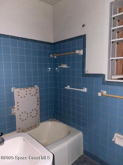 full bathroom with tile walls, wainscoting, a tub, and walk in shower