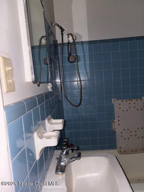 bathroom with tile walls, a shower, and a sink