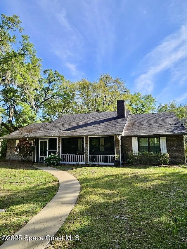 single story home with a chimney, a front lawn, and a sunroom