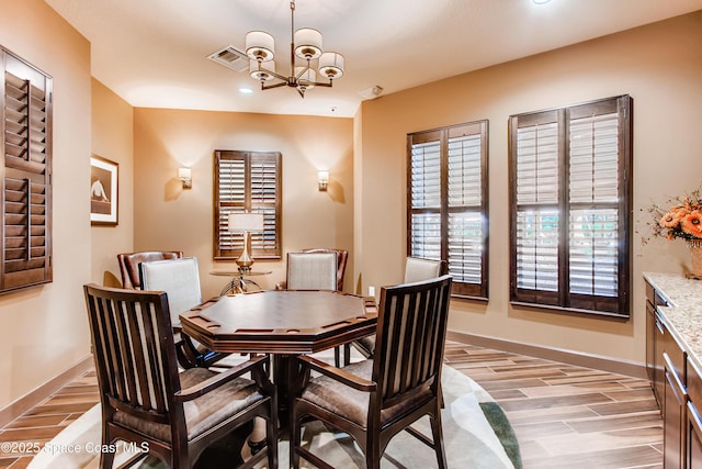 dining space featuring light wood finished floors, visible vents, baseboards, and a notable chandelier