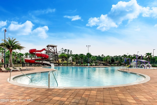 pool with a patio area, fence, and a water slide