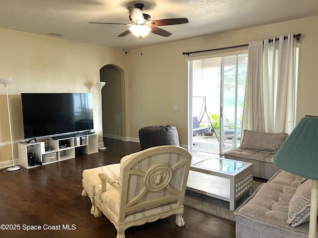 living area featuring visible vents, arched walkways, wood finished floors, and a ceiling fan