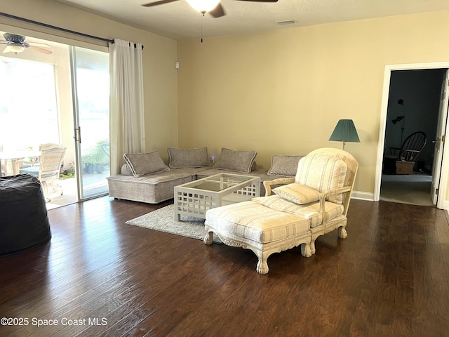 living room featuring visible vents, dark wood-type flooring, and ceiling fan