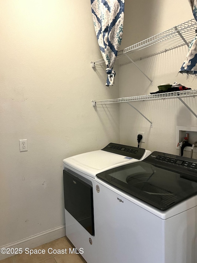 laundry area featuring baseboards, light tile patterned flooring, laundry area, and washing machine and clothes dryer