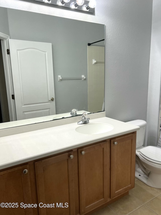 bathroom with toilet, vanity, and tile patterned flooring