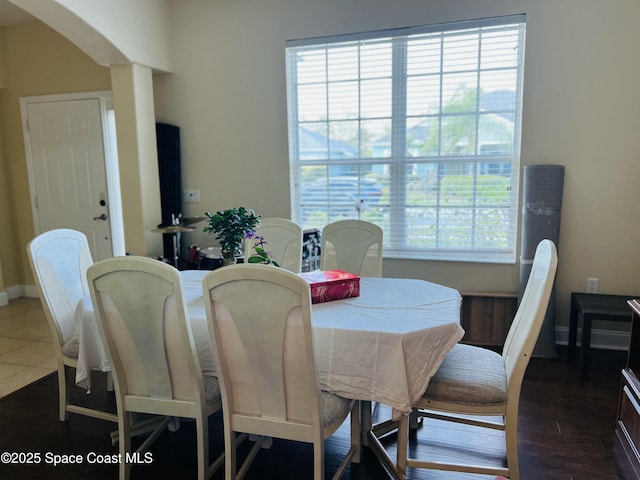 dining area with baseboards, arched walkways, and dark wood-style flooring