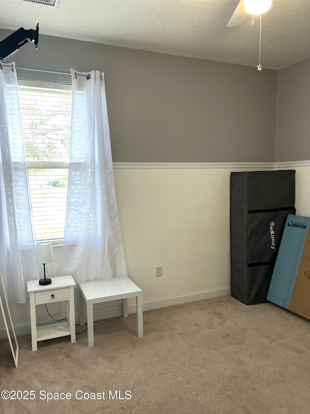 living area with carpet flooring, a ceiling fan, and visible vents