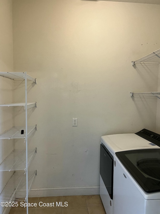washroom with washing machine and clothes dryer, baseboards, and light tile patterned floors