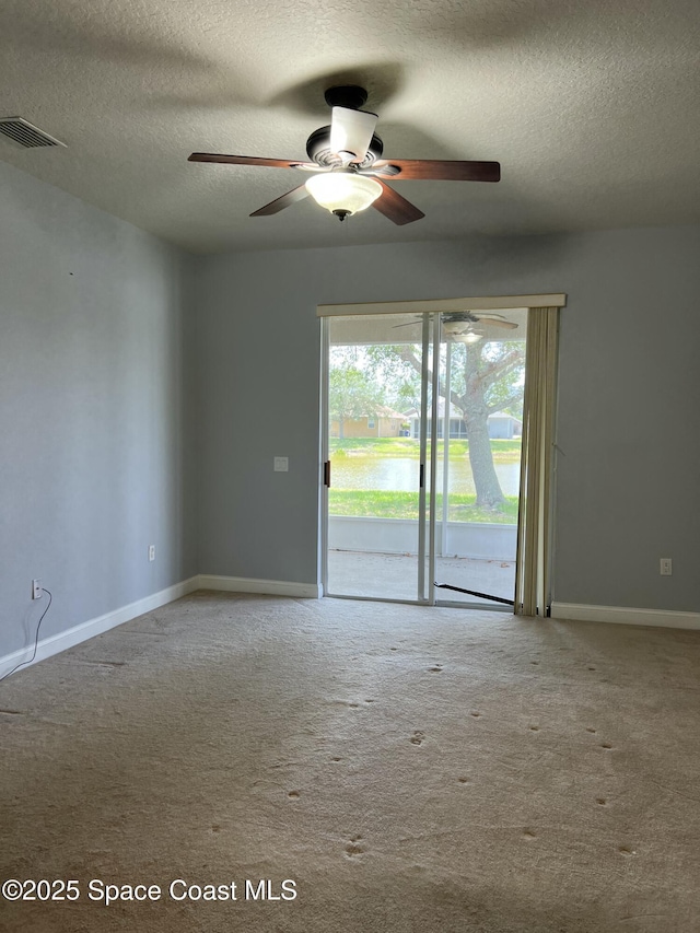 spare room with a textured ceiling, ceiling fan, carpet floors, and baseboards