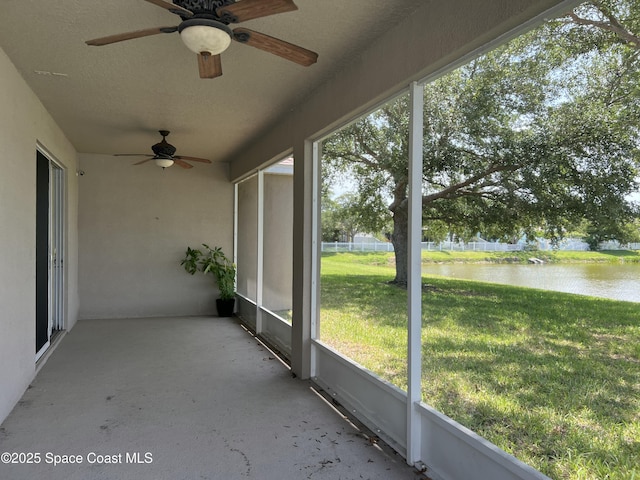 unfurnished sunroom featuring a water view and ceiling fan