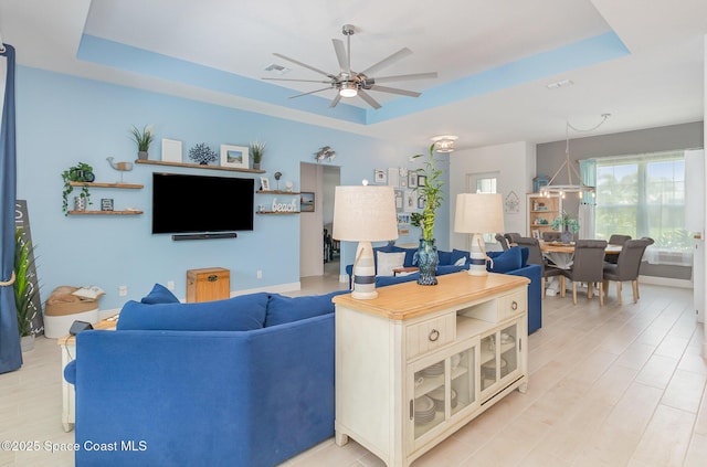 living room with visible vents, ceiling fan, and a tray ceiling