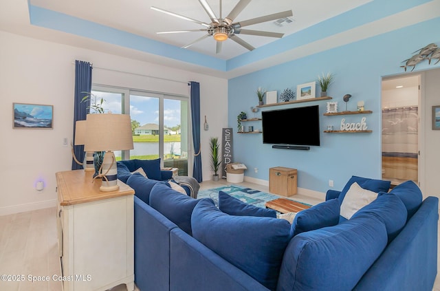 living room with visible vents, a raised ceiling, baseboards, and a ceiling fan