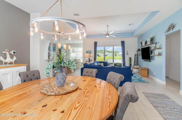 dining space featuring visible vents, baseboards, a tray ceiling, and a ceiling fan