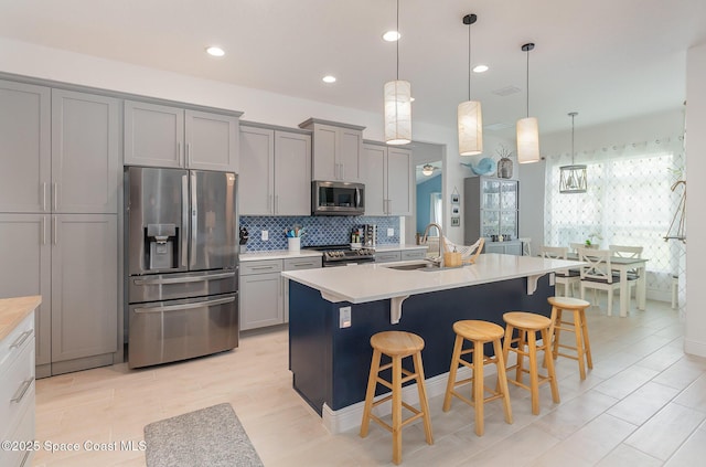 kitchen with decorative backsplash, gray cabinets, appliances with stainless steel finishes, and a sink