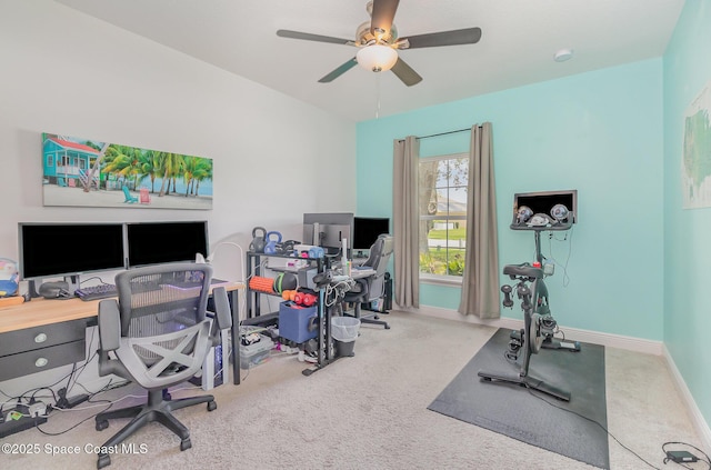 carpeted office space featuring baseboards and a ceiling fan