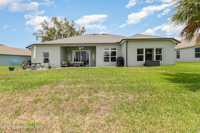 back of property with stucco siding, a ceiling fan, outdoor lounge area, and a yard