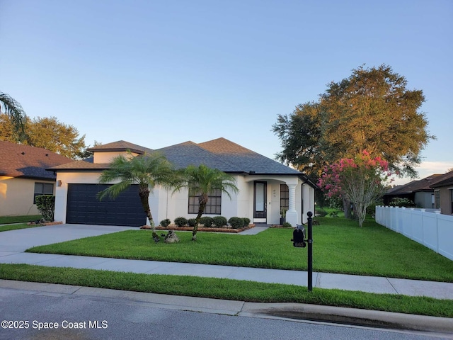 view of front of house with a front lawn, fence, driveway, and stucco siding