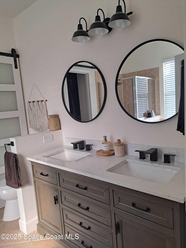 bathroom with double vanity, toilet, a stall shower, and a sink