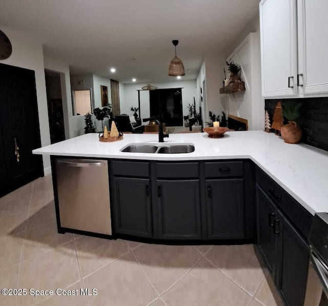 kitchen featuring light tile patterned floors, a peninsula, a sink, light countertops, and dishwasher