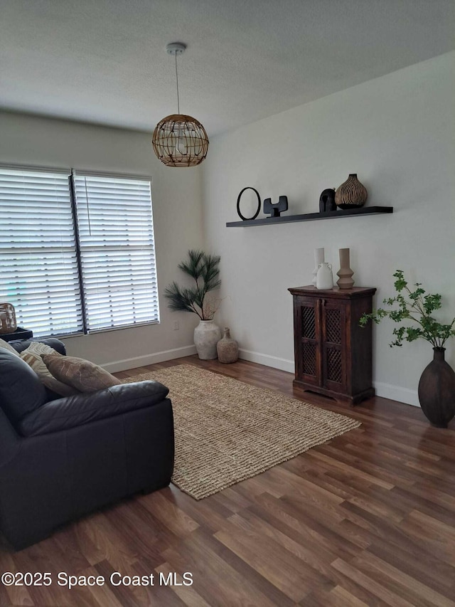 living room with baseboards, a textured ceiling, and wood finished floors