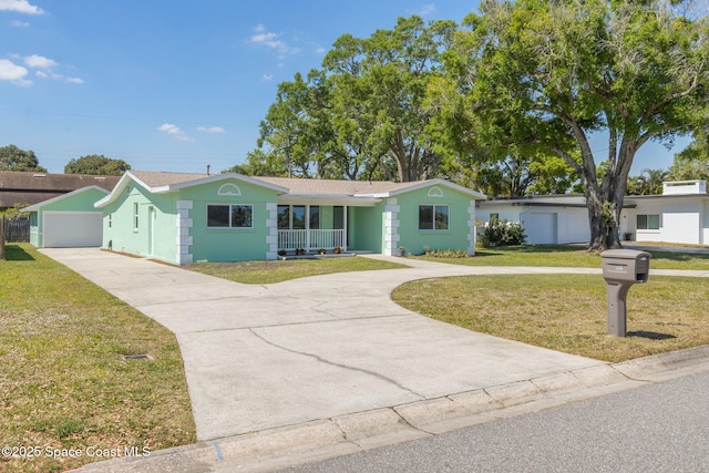 ranch-style home with a front yard, driveway, and a detached garage