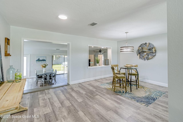 dining room with a textured ceiling, wood finished floors, visible vents, and baseboards