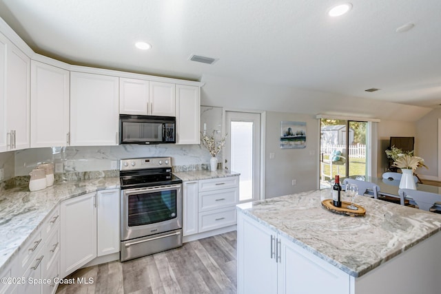 kitchen with visible vents, black microwave, light wood-type flooring, stainless steel range with electric stovetop, and white cabinetry