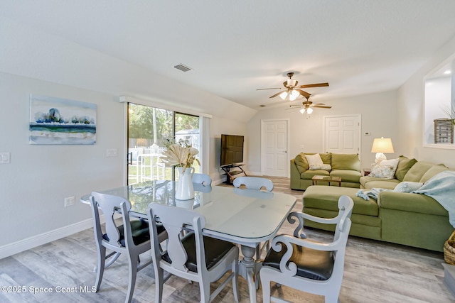 dining room with visible vents, light wood-style floors, ceiling fan, and vaulted ceiling