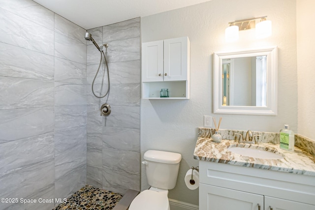 full bathroom with vanity, toilet, and tiled shower